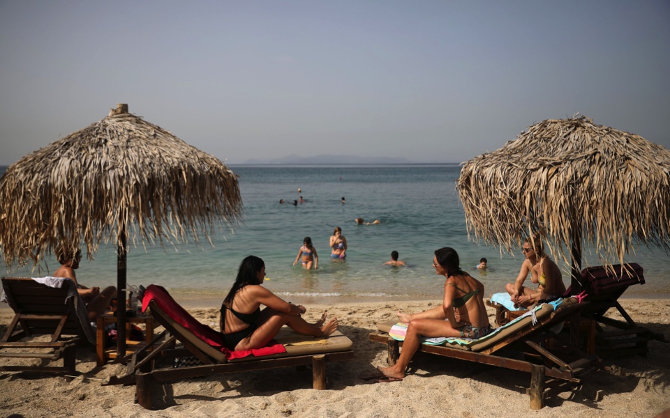 Greeks return to beaches in heatwave, but keep their umbrellas apart