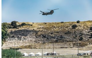 A Chinook helicopter flies tents to a makeshift camp on Lesvos