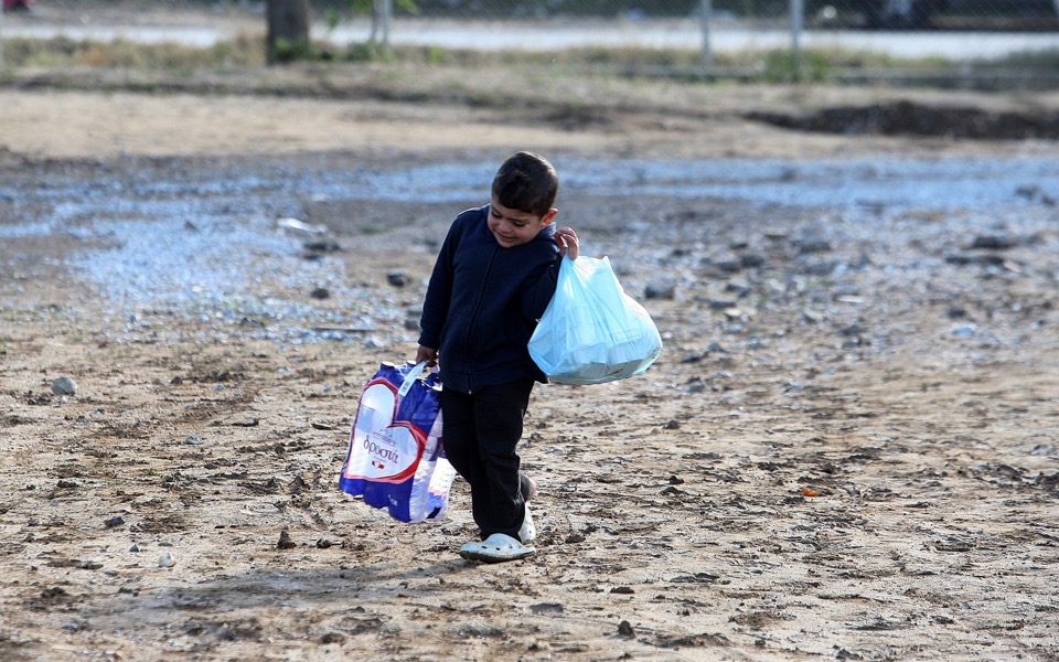 Young refugee carries supplies through muddy camp